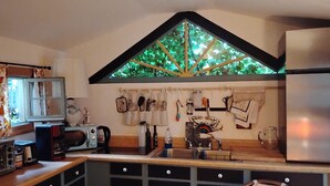Eine Küche mit integriertem Fenster, einem Kühlschrank, Schränken, einer Spüle und verschiedenen Küchengeräten.