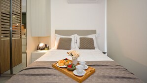 Una cama bien hecha con una bandeja de desayuno, una lámpara de noche y un equipo de aire acondicionado arriba.