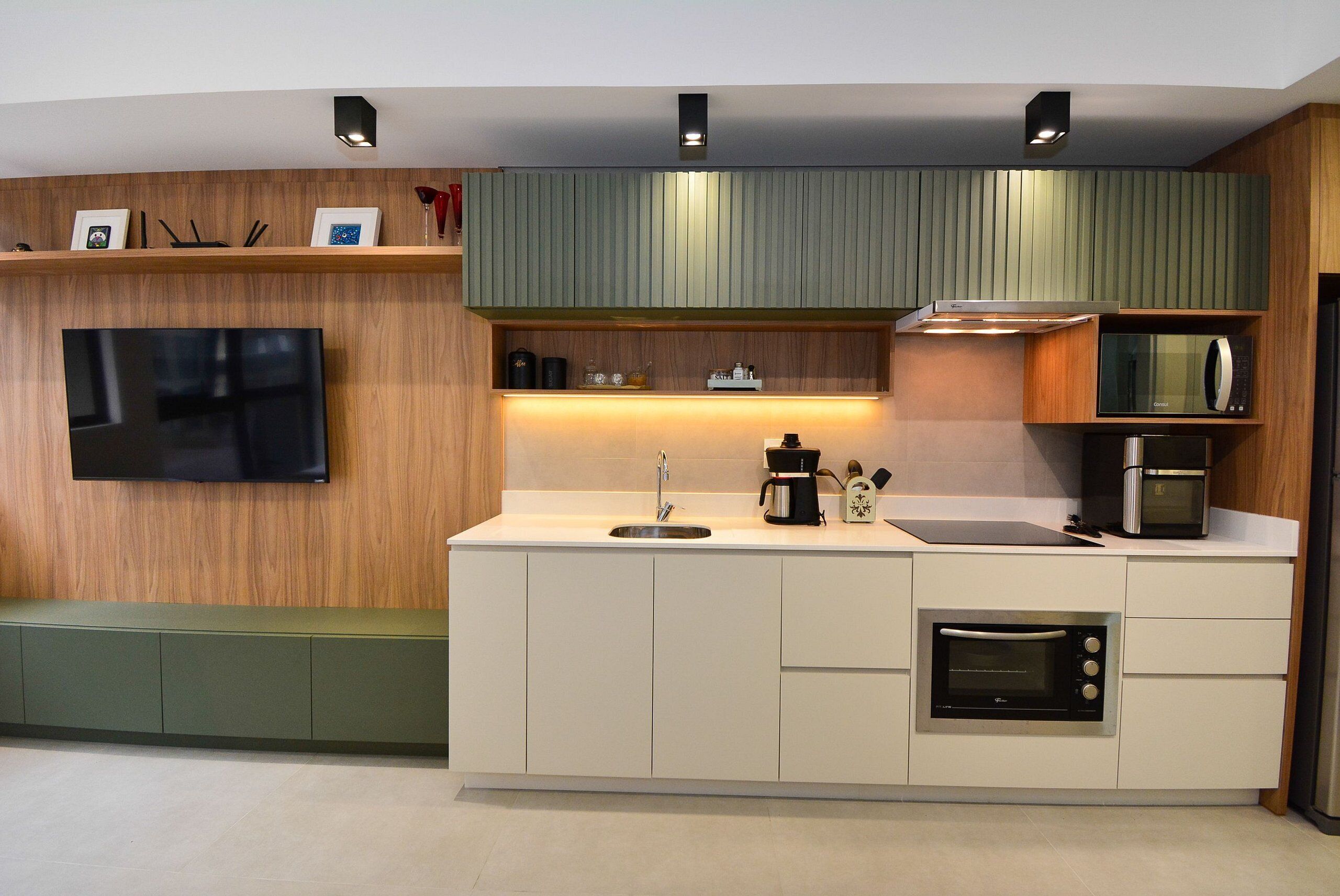 A modern kitchen with a flat-screen TV, built-in microwave, and coffee maker.