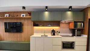 Una cocina moderna con televisor de pantalla plana, microondas integrado y cafetera.