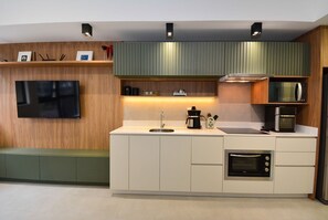 Una cocina moderna con televisor de pantalla plana, microondas integrado y cafetera.