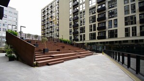 Un edificio moderno con una escalera que conduce a un piso superior, rodeado de otros edificios de gran altura.