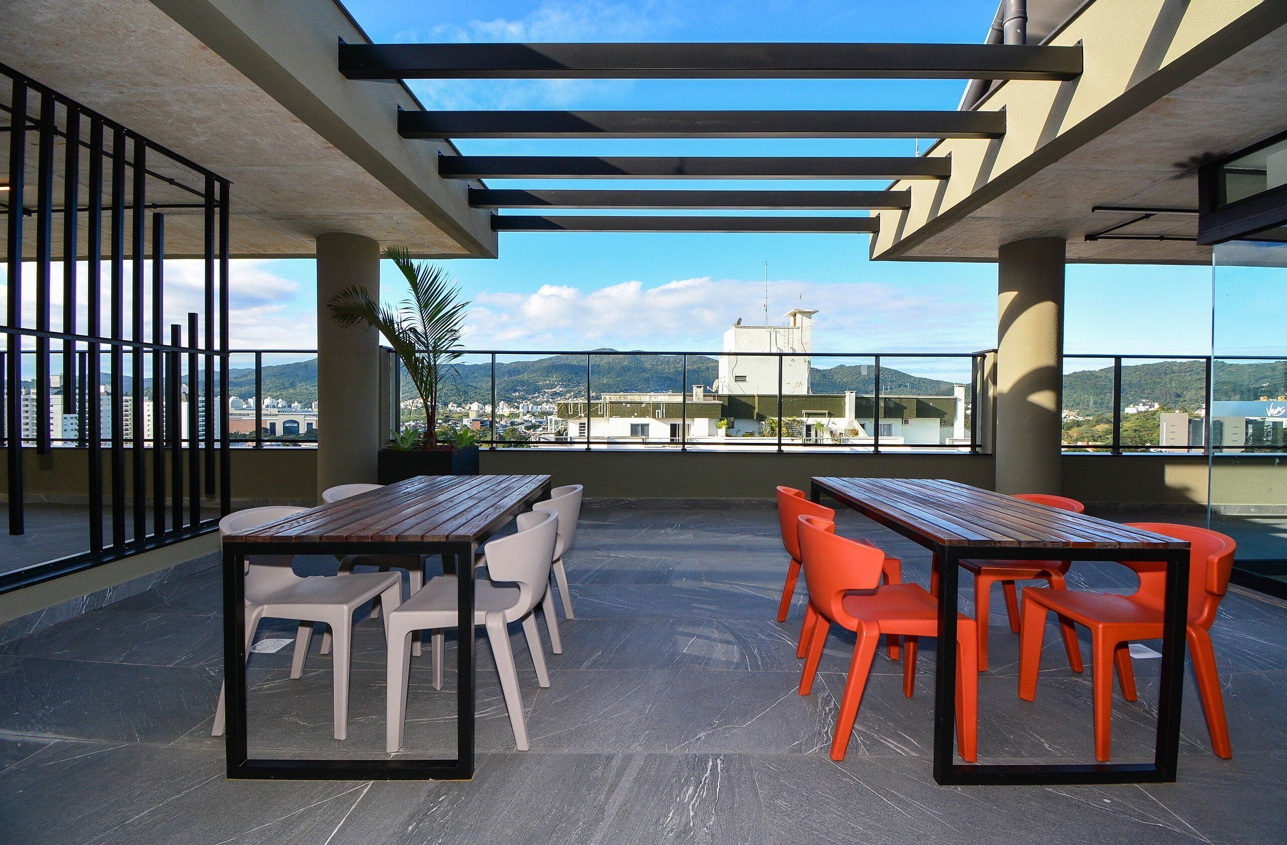 A rooftop terrace with outdoor seating, a pergola, and a view of the cityscape.