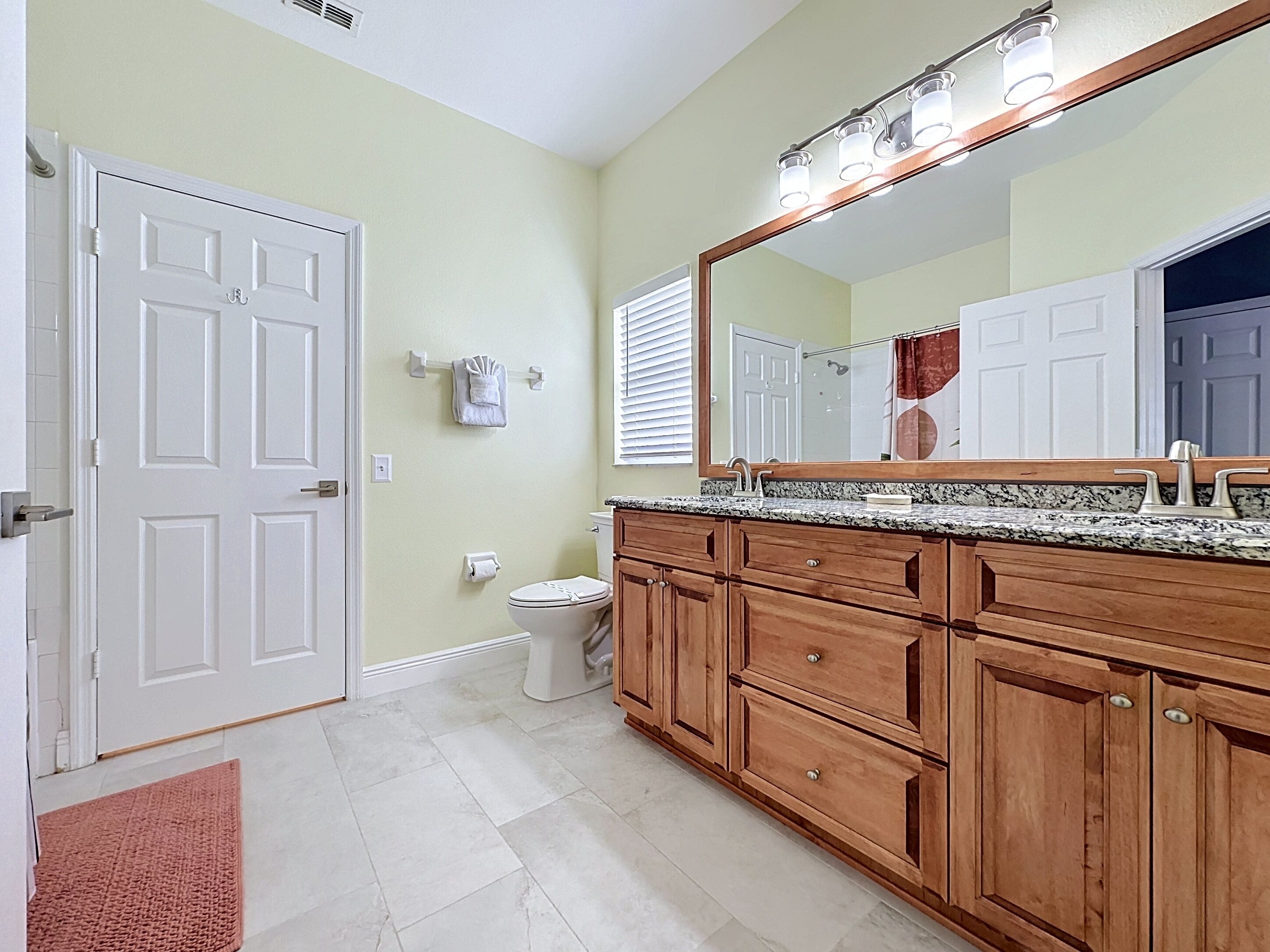 A bathroom with a wooden vanity, a large mirror, and a toilet.