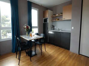 A modern kitchen with a dining table, chairs, and a view of the outdoors. - Apartment With Loft in Holiday Park (Chatel-Guyon)