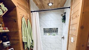 A wooden interior with a shower area, patterned floor tiles, and a bench. - Forest Ridge Cabin - Pet Friendly - Sleeps 10 (Ahwahnee)