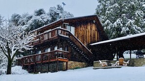 A wooden cabin with a balcony and a covered area with Adirondack chairs. - Forest Ridge Cabin - Pet Friendly - Sleeps 10 (Ahwahnee)