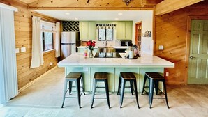 A kitchen with a central island, bar stools, and wooden walls. - Forest Ridge Cabin - Pet Friendly - Sleeps 10 (Ahwahnee)