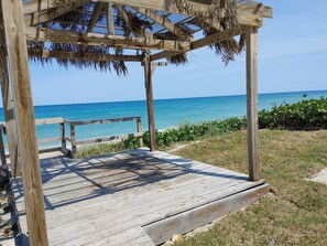 Ein hölzernes Pavillon mit einem Reetdach mit Blick auf einen Strand.