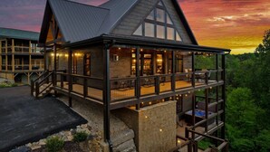 Eine zweistöckige Lodge mit Balkon, Whirlpool und Blick auf den umliegenden Wald.