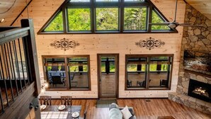 Ein geräumiger Loft mit hohen Decken, großen Fenstern, einem Kamin aus Stein und einem Essbereich.