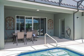 Ein Außenpoolbereich mit Tisch und Stühlen, einer Poolleiter und einer überdachten Terrasse.