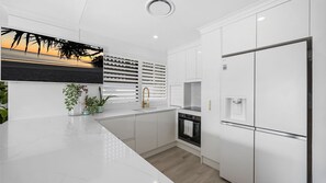 A modern kitchen with white cabinetry, a built-in oven, and a stainless steel refrigerator. - luxurious 2 bedroom unit on Maroochydore River (Maroochydore)