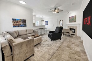 Una sala de estar con sofá, sillón, chimenea y obras de arte.