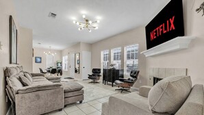 A modern living room with a fireplace, a flat-screen TV, and a large window. - TikTok: Walk to Texas A&M Campus, Sleep 8, 3BR/3BA (College Station)