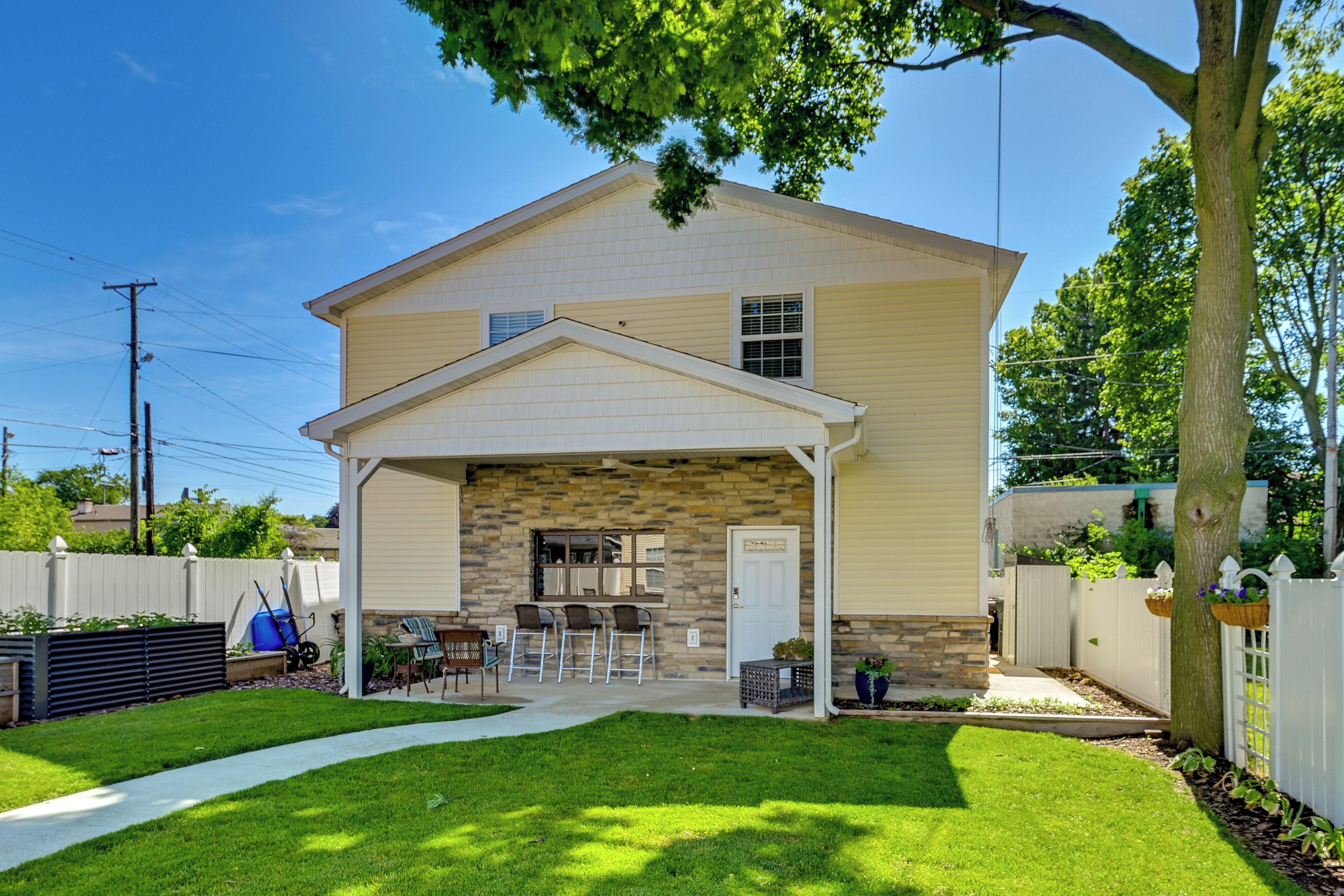 A two-story house with a covered patio, a stone exterior, and a well-maintained lawn.