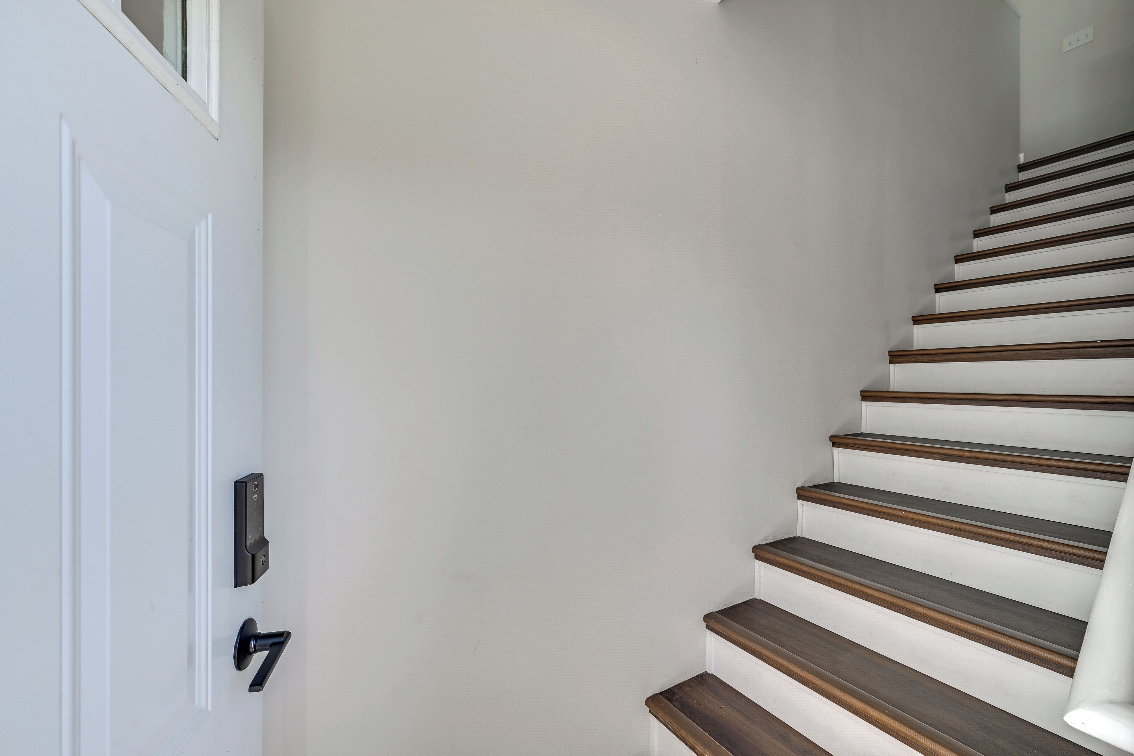 Una escalera de madera con un muro blanco.
