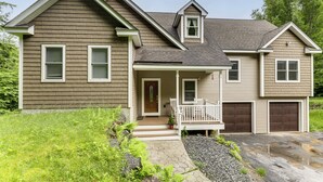 A two-story house with a front porch, a small attached garage, and a stone pathway leading to the entrance. - Waterville Getaway w/ Private Hot Tub (Campton)
