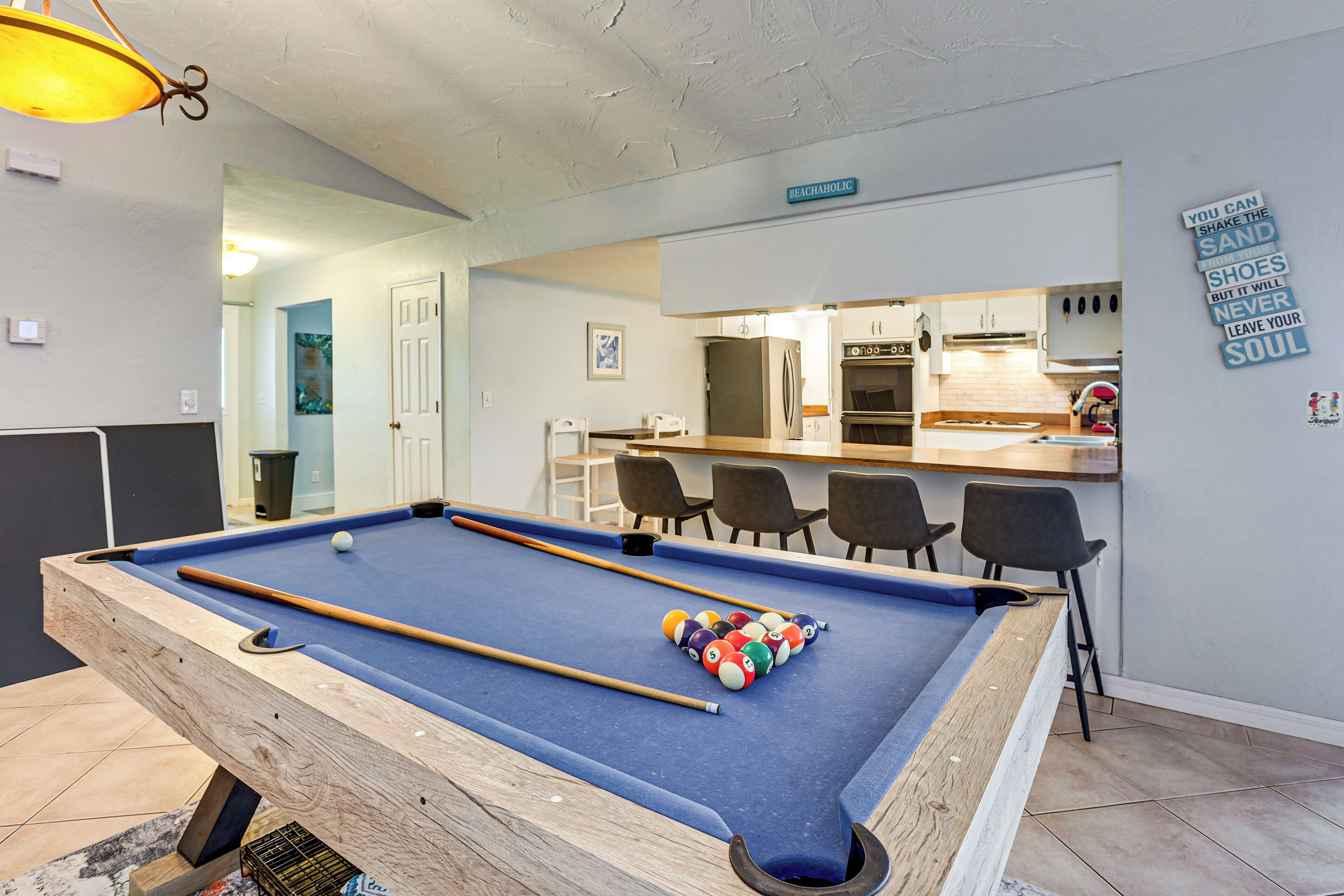 A pool table with balls, a kitchen area, and a bar.