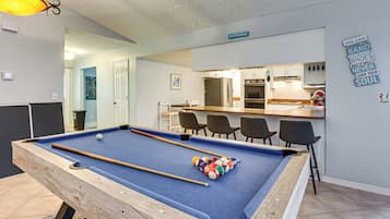 A pool table with balls, a kitchen area, and a bar.