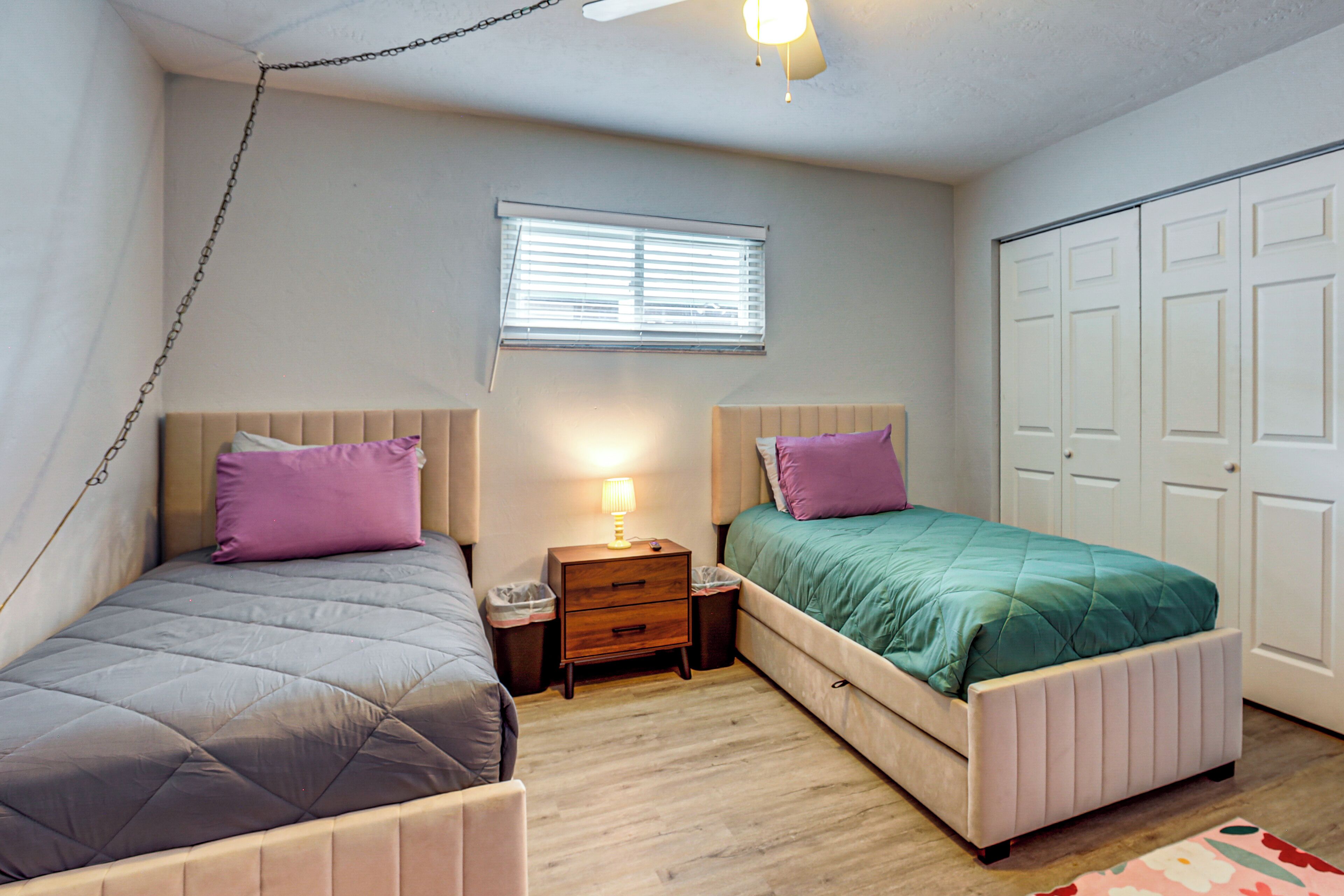 Una camera da letto con due letti, una finestra, un comodino con lampada e un armadio.