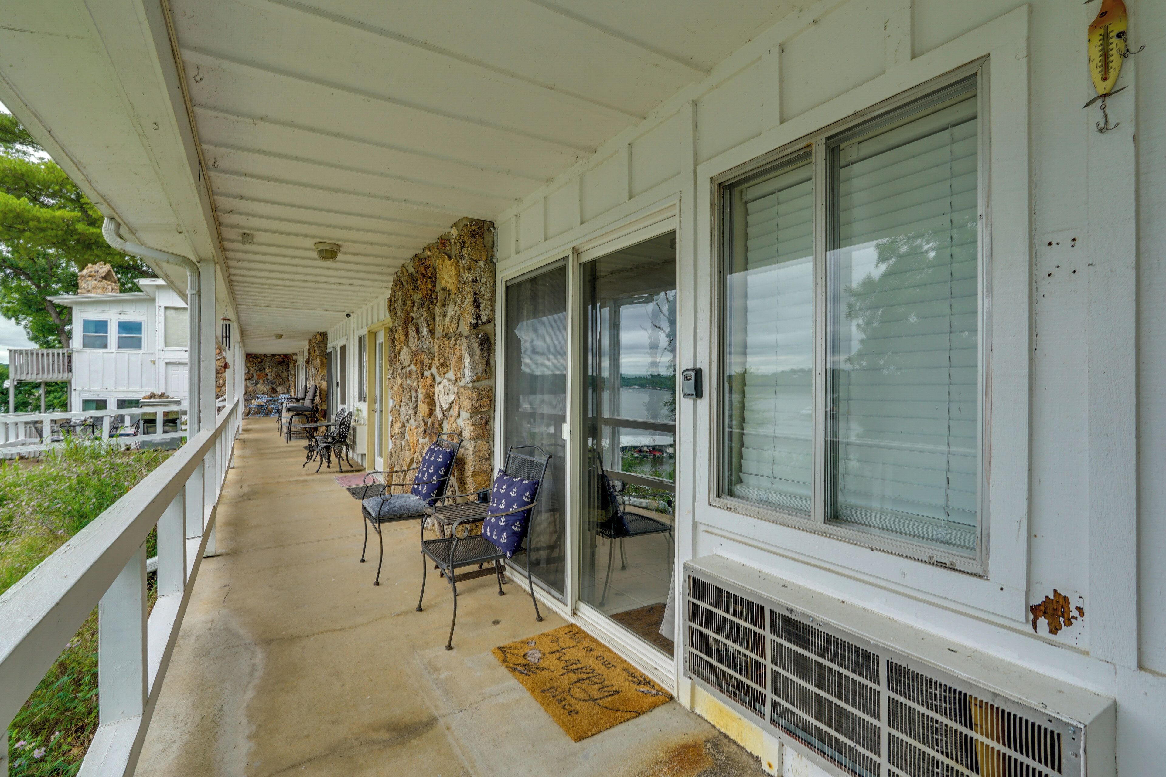 A covered porch with chairs, a stone wall, and a large window.
