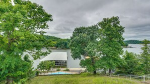 Vista de un lago con un edificio moderno, piscina y abundante vegetación.