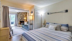 Un dormitorio con una cama grande, una chimenea de piedra, un sofá y vistas al exterior.
