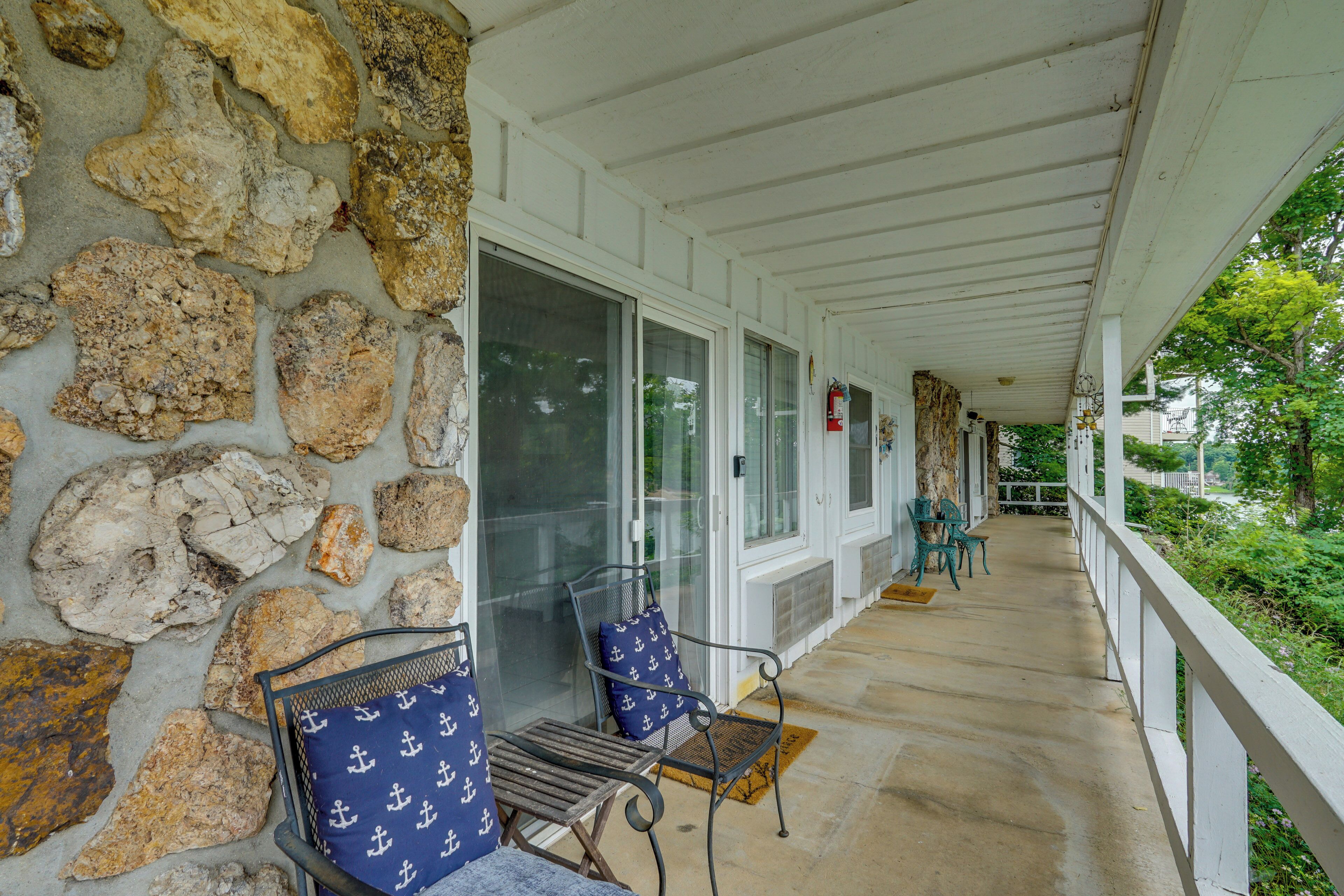A covered porch with stone walls, a fire extinguisher, and outdoor seating.