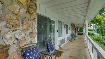 A covered porch with stone walls, a fire extinguisher, and outdoor seating.