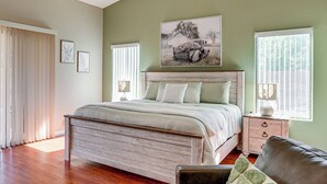 A bedroom with a wooden bed, two bedside tables, a window with blinds, and a painting on the wall. - 2 Mi to Surprise Stadium! Dog-friendly Home, Pool (Surprise)
