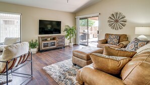 A living room with a ceiling fan, a flat-screen TV, a sofa, a coffee table, and a potted plant. - 2 Mi to Surprise Stadium! Dog-friendly Home, Pool (Surprise)