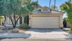 A residential house with a garage, a driveway, and landscaping including rocks and trees. - 2 Mi to Surprise Stadium! Dog-friendly Home, Pool (Surprise)
