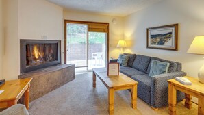 A living room with a fireplace, a sofa, a coffee table, and a lamp. - Unwind Poolside, Walk to Main St! Winter Park Stay (Winter Park)