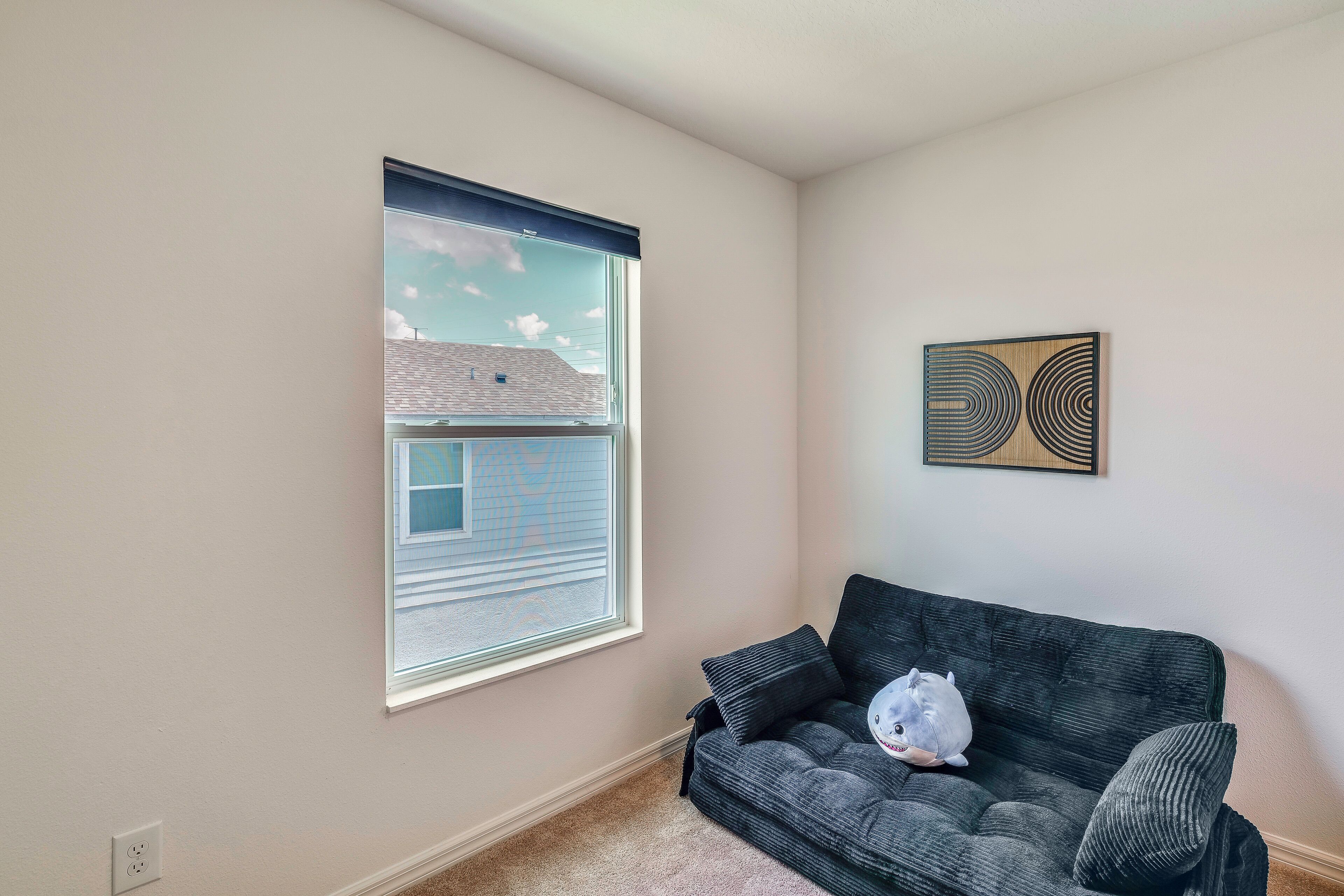 A room with a window, a gray couch, and a wall-mounted artwork.