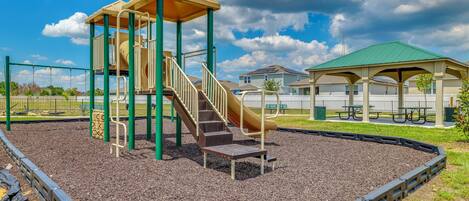 A playground with a slide, a climbing structure, and a covered seating area.