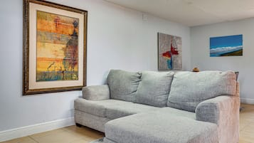 Un soggiorno con un divano modulare grigio, un quadro astratto incorniciato e un dipinto di paesaggio appeso al muro.