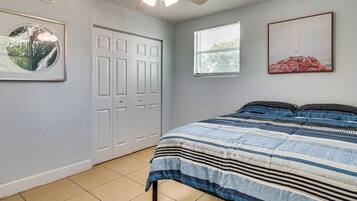 Ein Schlafzimmer mit Bett, Deckenventilator, Fenster und Tür.