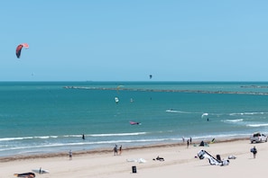 Ein Strand mit Menschen, einer Mole und einem klaren Himmel.