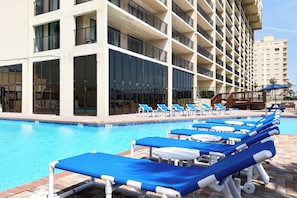 Ein Hotelpoolbereich mit mehreren Balkonebenen, klarem blauen Wasser und Liegestühlen.