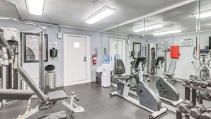Et fitnessrum med træningsudstyr, en drikkefontæne og et spejl.
