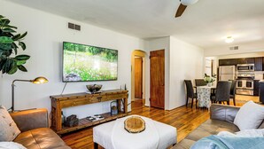 Ein Wohnzimmer mit einer Couch, einem Couchtisch, einem Fernseher und einem Essbereich mit Stühlen und einem Tisch.