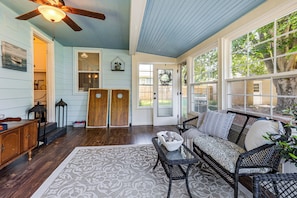 A room with a ceiling fan, a sofa, a patterned rug, and a view of the outdoors.