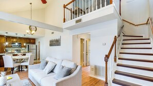A spacious living area with a sofa, dining table, and kitchen in the background.