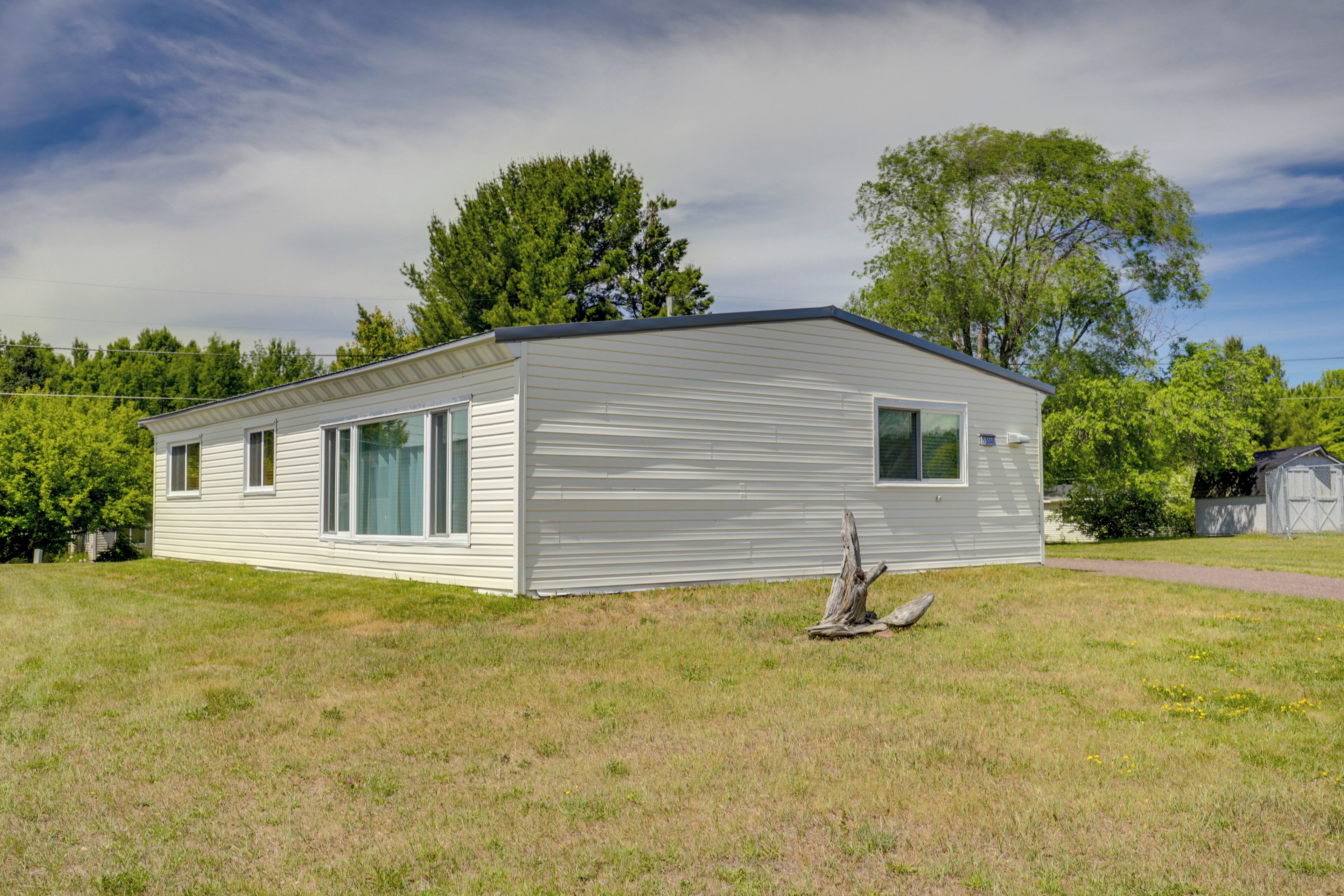Une maison mobile de plain-pied, dotée d’un toit plat, de grandes fenêtres et d’un porche à l’avant.