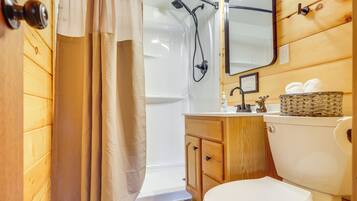 A wooden-paneled bathroom with a shower, toilet, vanity, and mirror.