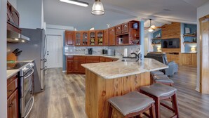 A kitchen with wooden cabinets, a marble island, and a bar area with stools.