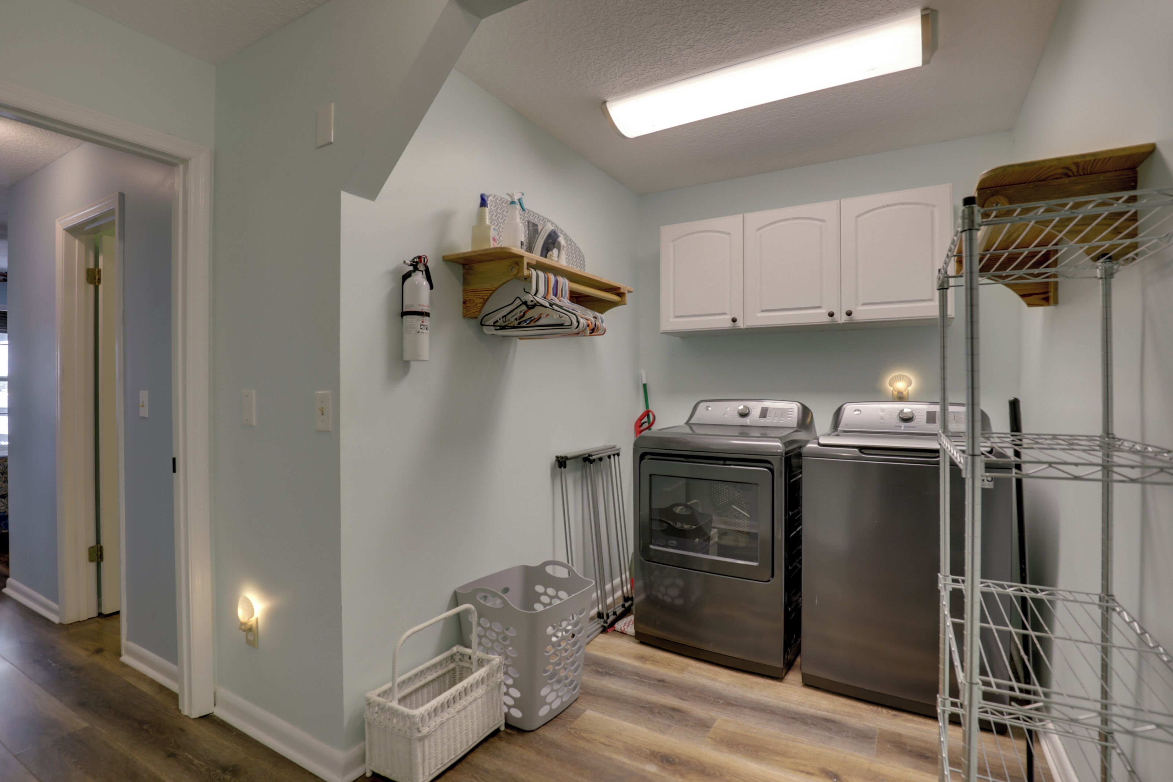 A laundry room with a washing machine, dryer, and metal shelving unit.
