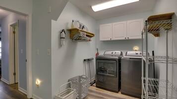 A laundry room with a washing machine, dryer, and metal shelving unit.