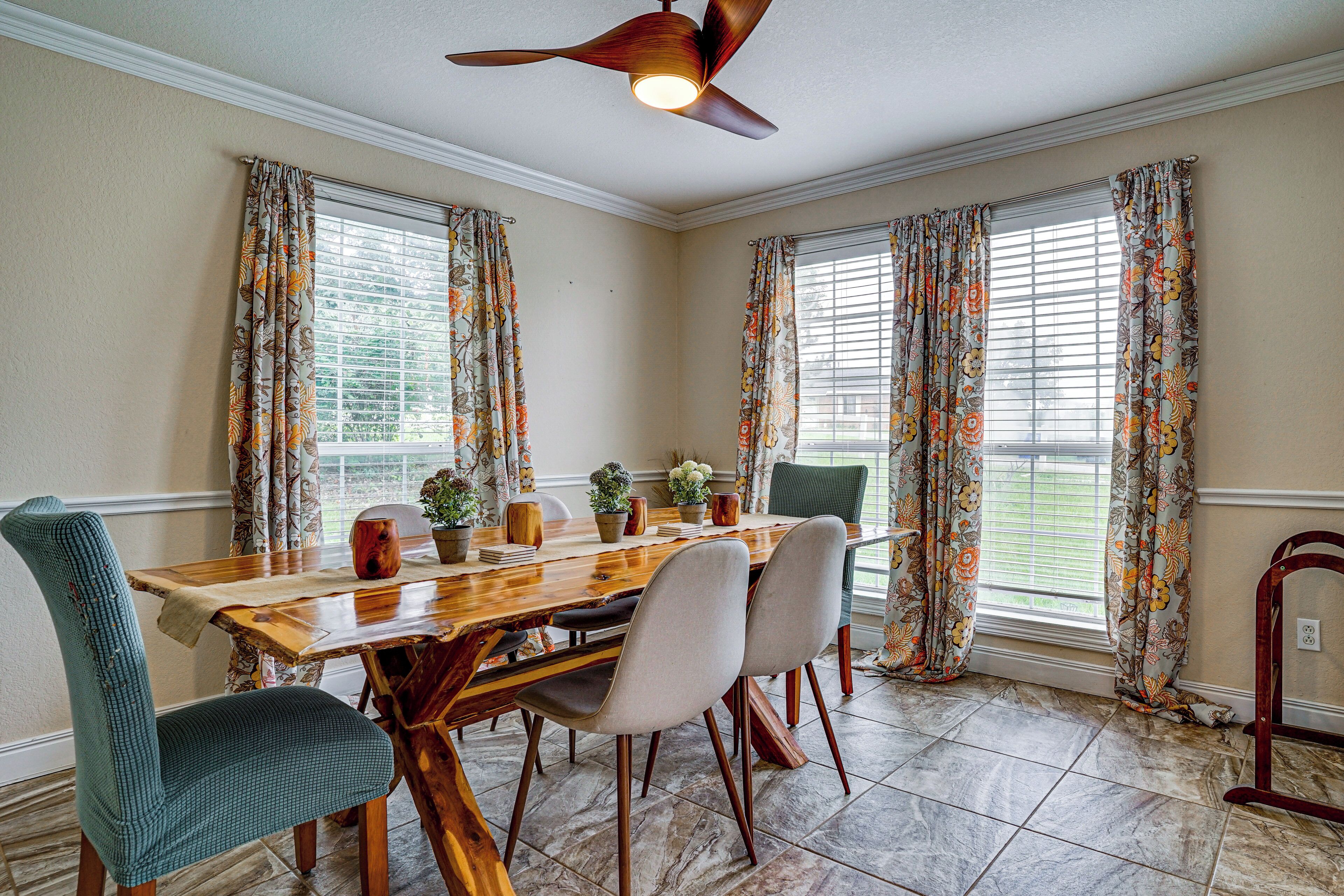 A dining room with a wooden table, chairs, and a ceiling fan.